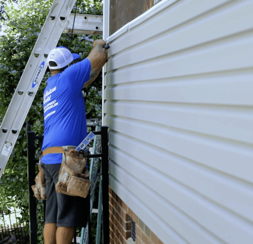 Window World installer installing vinyl siding on a home.